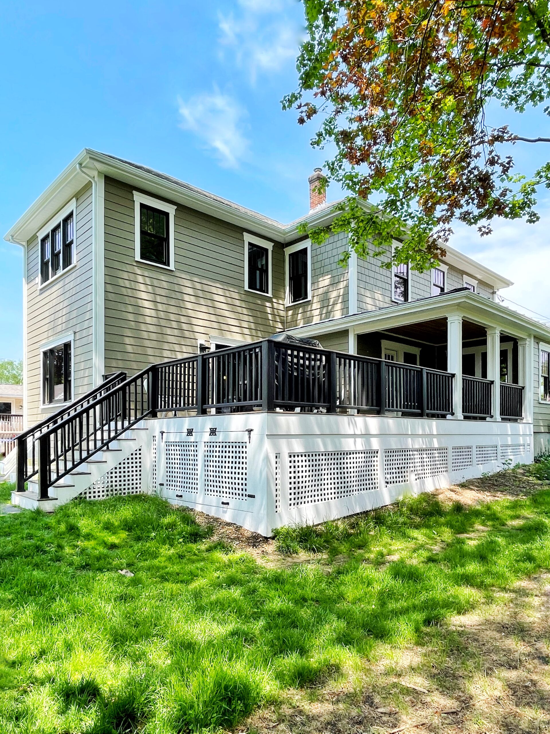 Large composite deck wrapping a sage green home
