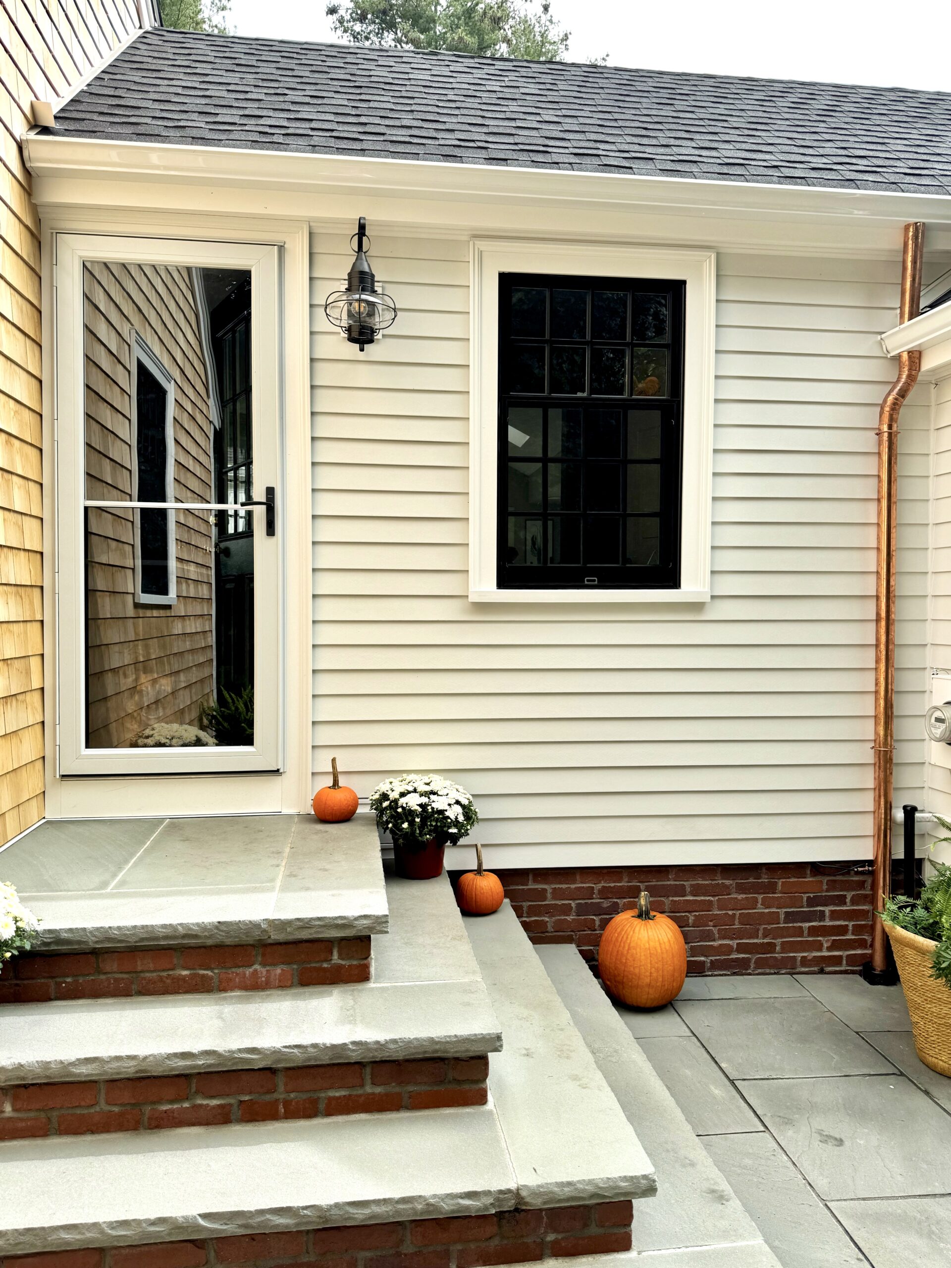 Copper downspout on cream siding