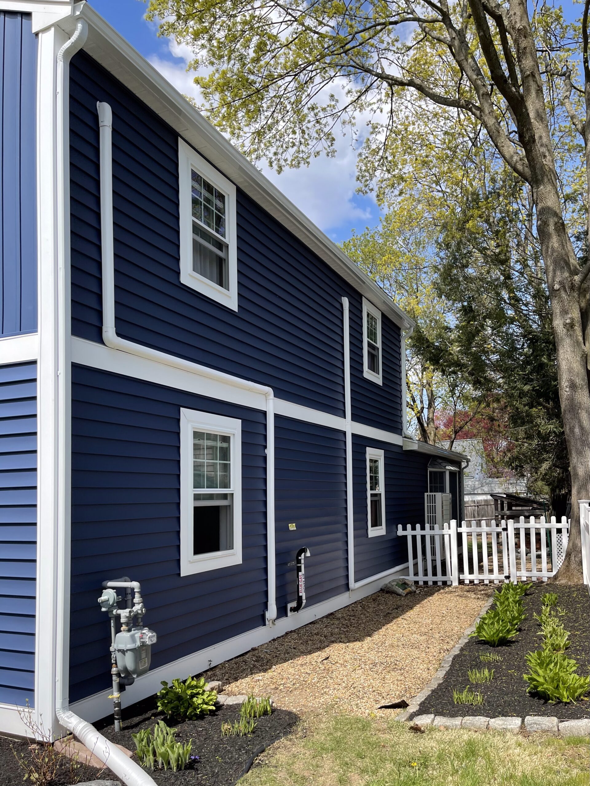 White aluminum downspout on a Natick home with navy siding