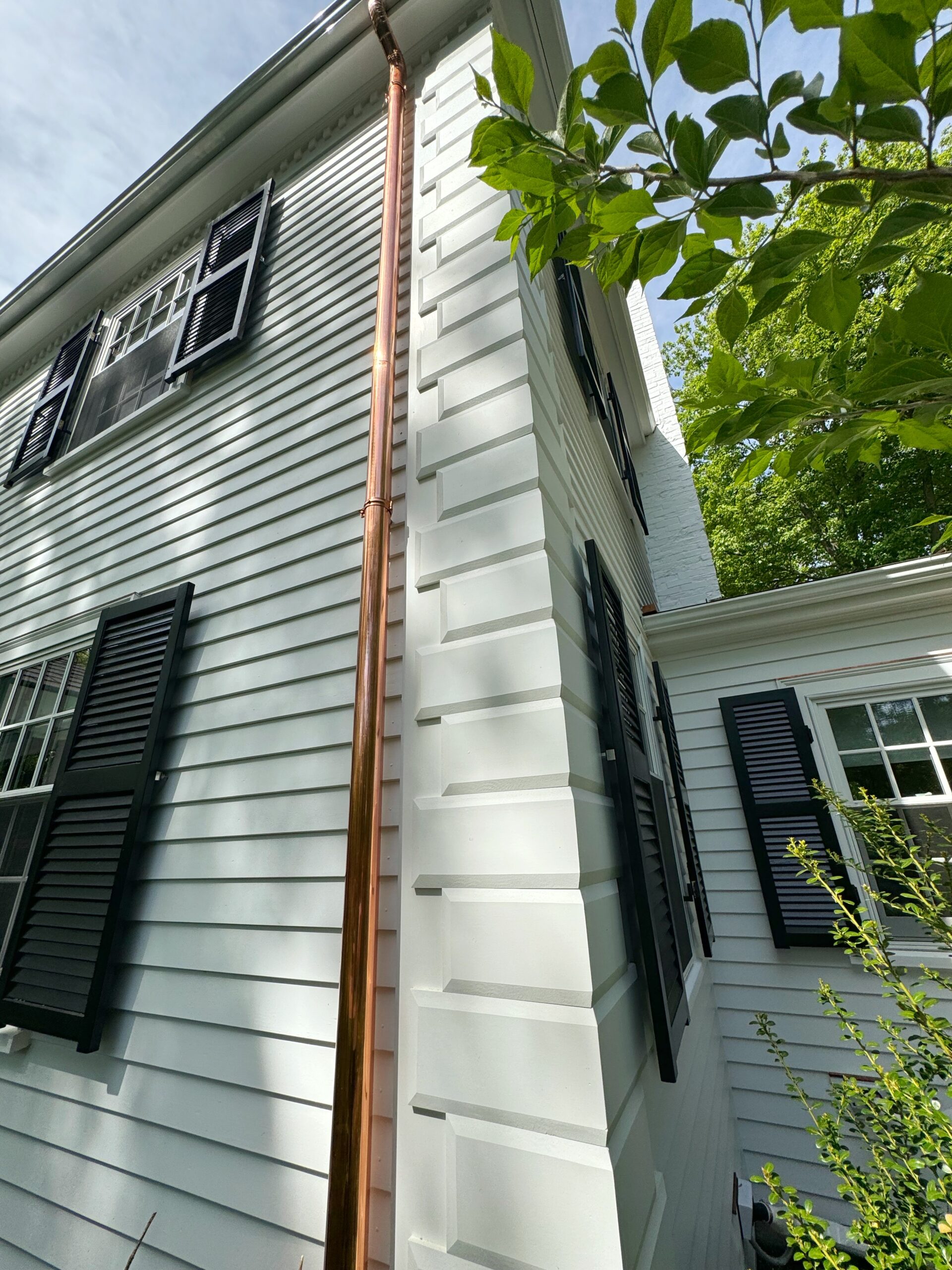 Copper downspout on painted cedar siding