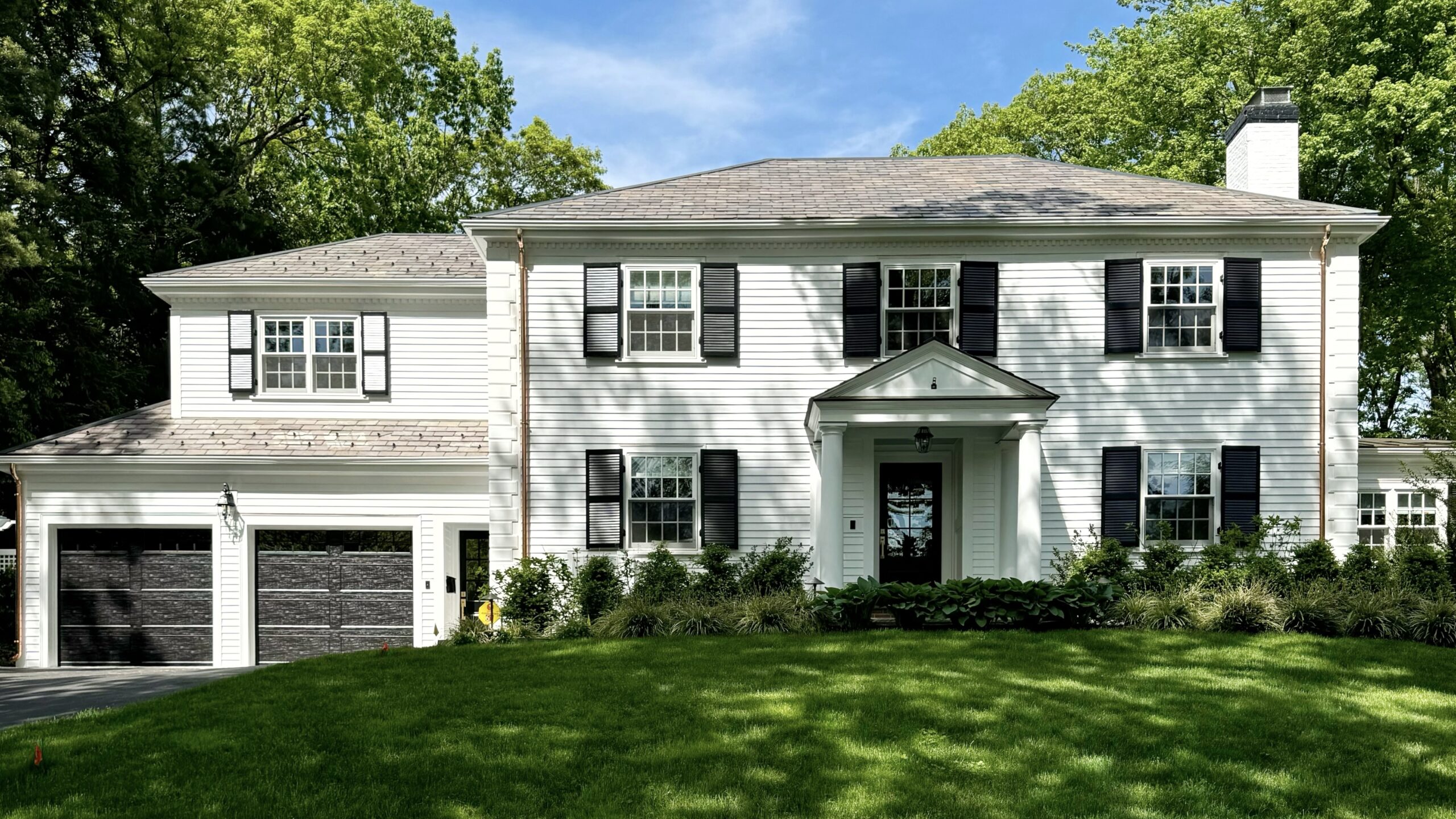 White Wellesley colonial with painted cedar siding and black shutters