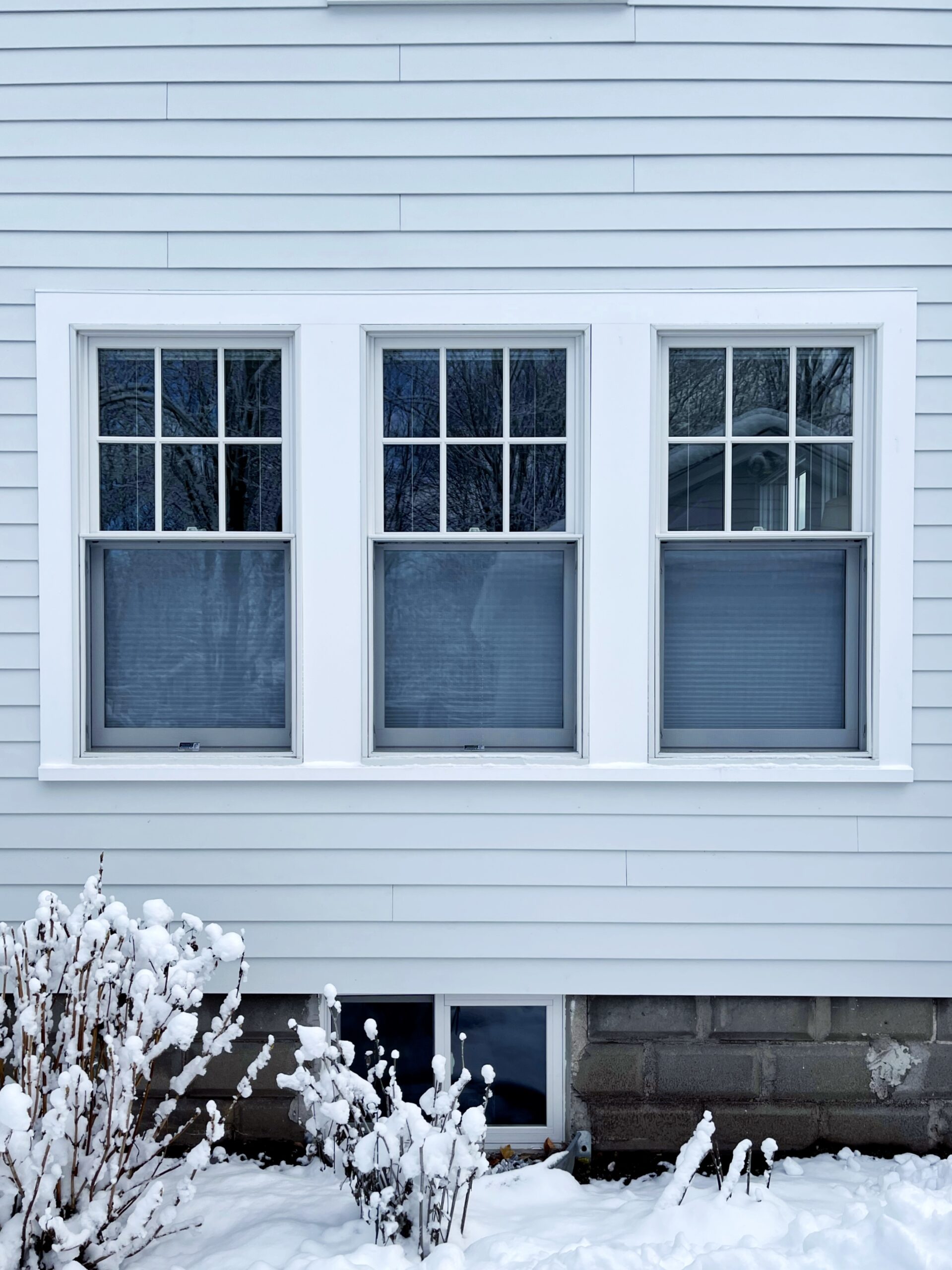 Three white double-hung windows in light blue siding